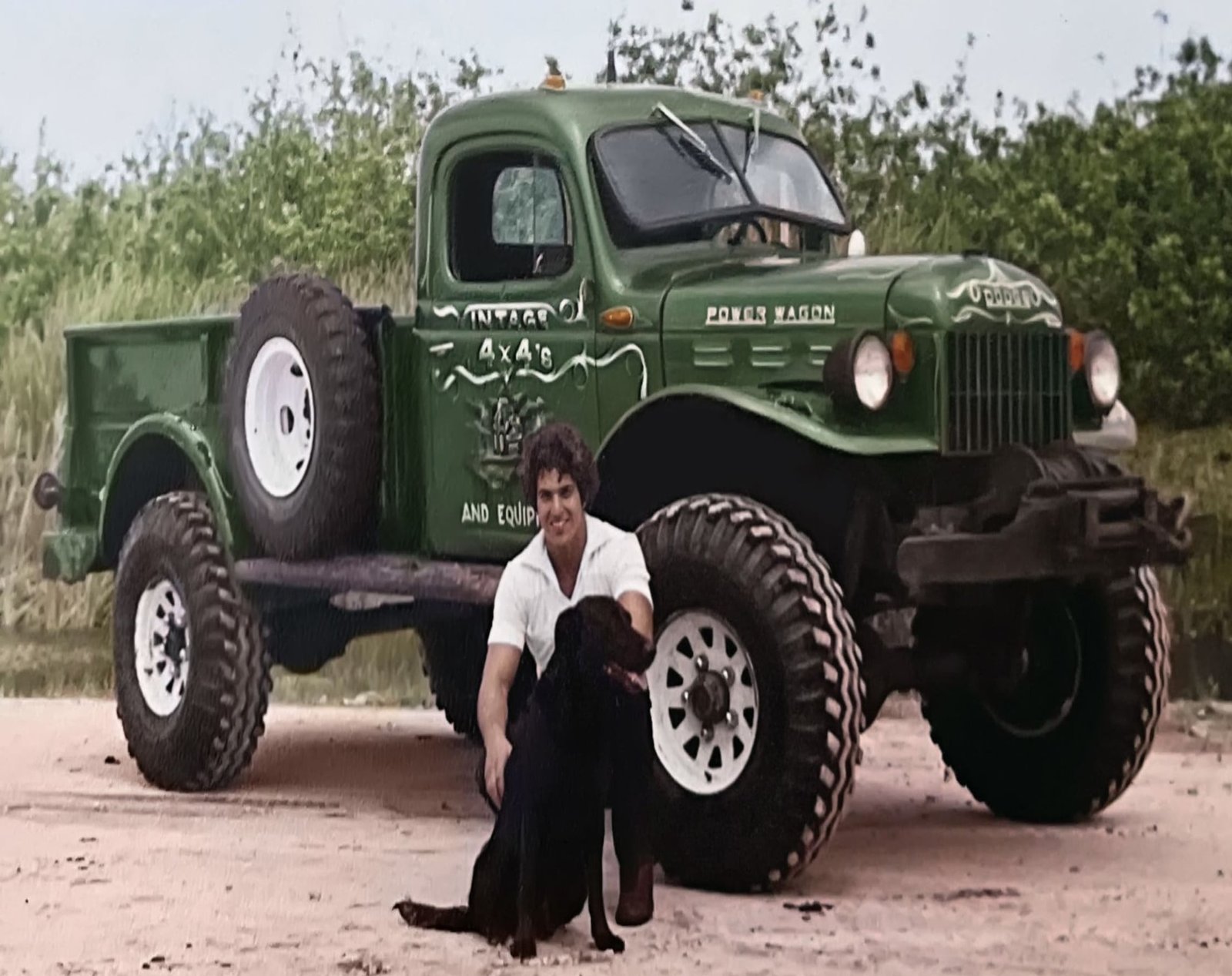 Thomas Rippy sitting with his dog beside a vintage green Dodge Power Wagon